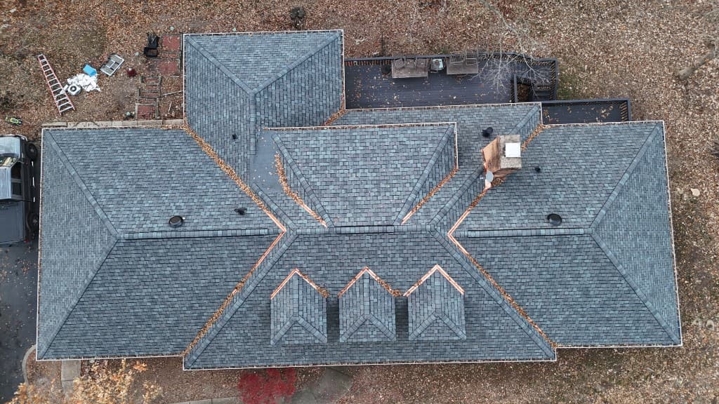 Tim Zolman property — top-down aerial before restoration showing asphalt shingle roof with debris in valleys, dormers, brick chimney, and autumn surround
