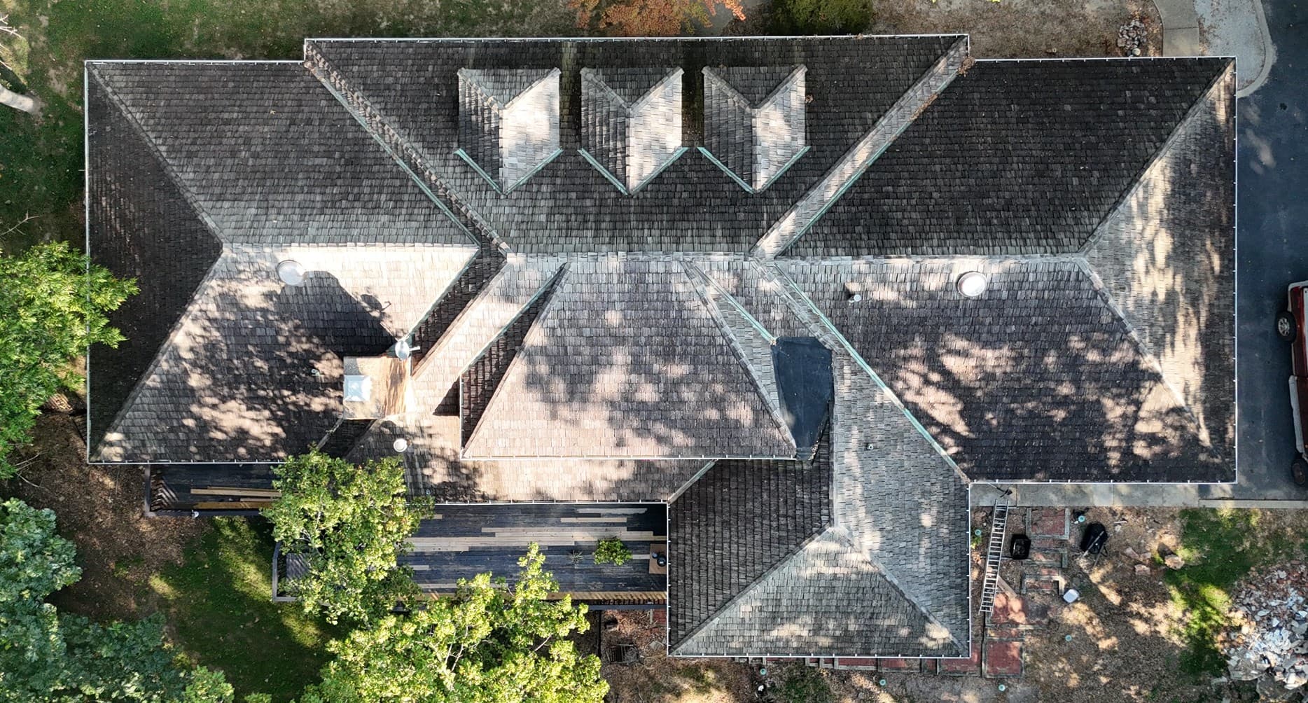Big Timber project — top-down aerial before restoration showing weathered cedar shake roof with sun-faded, mottled planes across the dormers and hip ridges