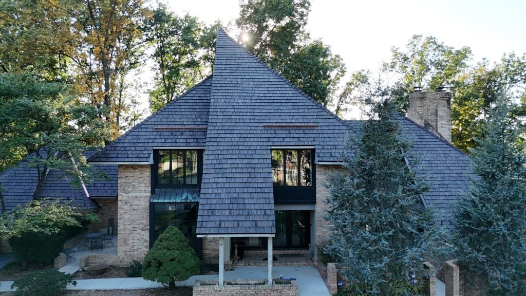 Completed residence — multi-gable cedar shake assembly with copper integration from an elevated wide aerial perspective
